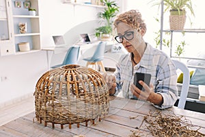 Woman at home doing hobby leisure activity following online tutorial on mobile phone. Modern people and internet content classes