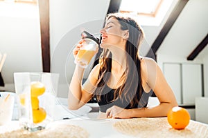 Woman at home drinking orange flavored amino acid vitamin powder.Keto supplement.After exercise liquid meal.Weight loss