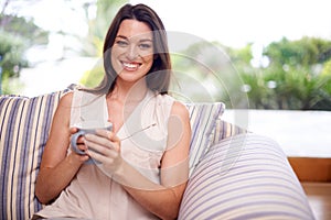 Woman, home and happy in couch with coffee to relax or chill on break, day off and enjoy. Portrait, female person and