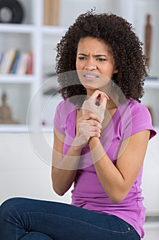 Woman at home holding so wrist