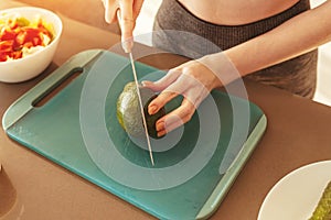 Woman in the home kitchen cutting an avocado for a healthy eating