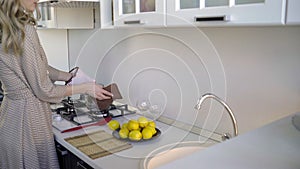 Woman at home in the kitchen preparing food stands with her back to the camera at the stove, large kitchen in modern