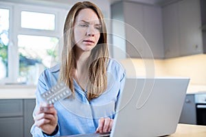 Woman At Home Looking Up Information About Medication Online Using Laptop