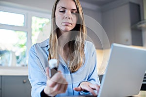 Woman At Home Looking Up Information About Medication Online Using Laptop