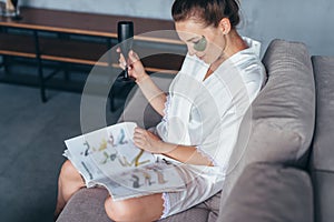 Woman at home in a nightgown with a magazine, a glass and patches on her face