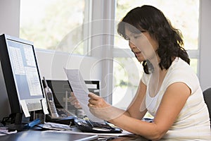 Woman in home office with computer and paperwork