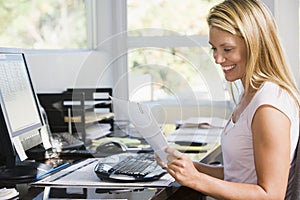 Woman in home office with computer and paperwork