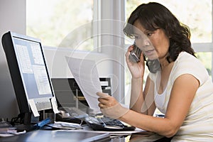 Woman in home office with paperwork on telephone