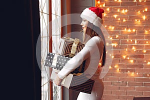 Beautiful girl standing near window with presents