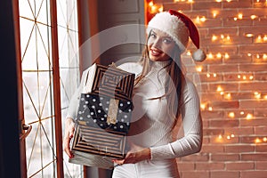 Beautiful girl standing near window with presents