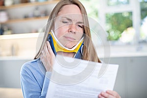 Woman At Home Reading Letter After Receiving Neck Injury