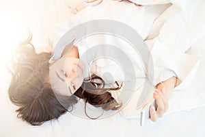 Woman at home reading a text message from smartphone in her bright bedroom