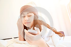 Woman at home reading a text message from smartphone in her bright bedroom