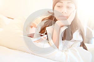 Woman at home reading a text message from smartphone in her bright bedroom