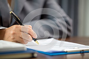 Woman home sales person is checking documents for house purchase contract before letting the customer sign contract on table is