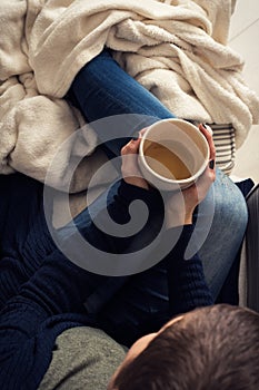 Woman at home sitting in comfy armchair and drinking tea