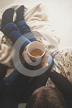 Woman at home sitting in comfy armchair and drinking tea, view from above