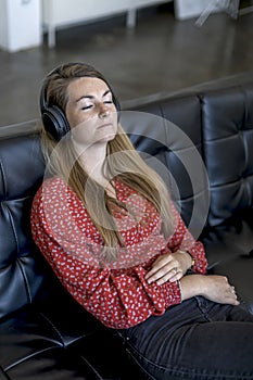 Woman at home sitting on couch wearing headphones