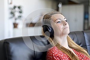 Woman at home sitting on couch wearing headphones