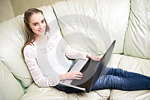 Woman at home sitting on sofa and using her laptop computer