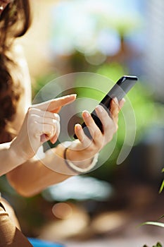 Woman at home in sunny day sending text message using smartphone