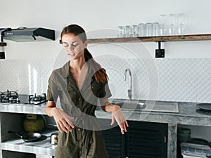 Woman at home tired in the kitchen prepares food using meat and vegetables, large modern style kitchen, lifestyle