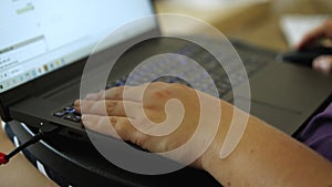 A woman at home working on a laptop. Close-up of the hand on the keyboard. The other hand moves the mouse. The concept of remote w