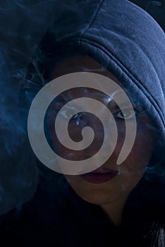 Woman hooded in darkness with smoke