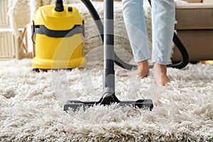 Woman hoovering carpet with vacuum cleaner