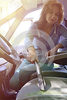 Woman hoovering a seat in car