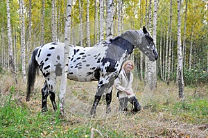 Woman with horse in a birch forest