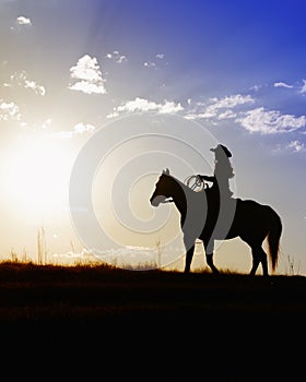 Woman on horse looking at beautiful sunset