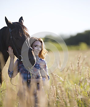 Woman and horse in the meadow at summer evening