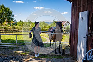 Woman with horse in stable at countryside ranch. Girl horse rider in summer outdoor. Equestrian and horseback riding. Horse