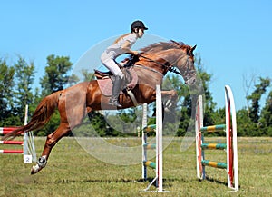 Woman horseback on jumping red chestnut horse