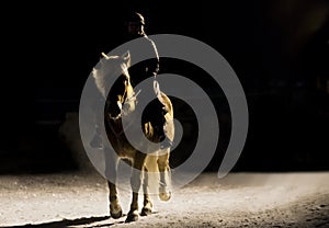 Woman horseback riding on country road at night