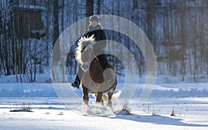 Woman horseback riding in winter snow