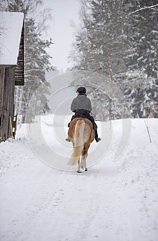 Woman horseback riding in winter snowfall