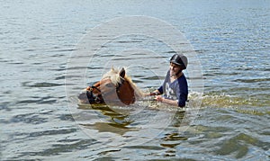 Woman horseback swimming on the lake