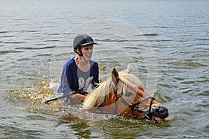 Woman horseback swimming on the lake