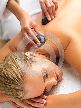 Woman, hot stone massage and spa with hands of masseuse, peace and treatment for destress at luxury resort. Serene, zen