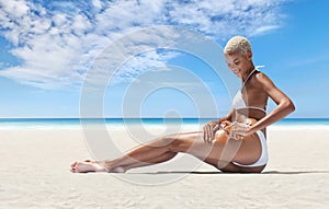 woman on the hot summer beach applying sunscreen lotion to buttocks skin for care and sun protection, in sunny sea day with blue