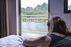 A woman on a hotel lying on a crawati looking at the resort. Girl looking at river over balcony