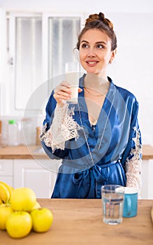 Woman in housecoat drinking protein shake for weight loss at breakfast in kitchen photo