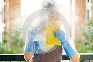 Woman housekeeper cleaning the mirror with yellow cloth