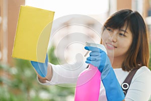 Woman housekeeper cleaning the mirror with yellow cloth.