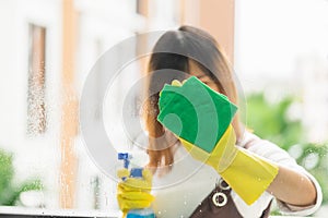 Woman housekeeper cleaning the mirror with yellow cloth