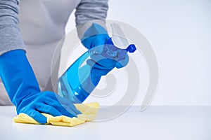 Woman housekeeper using rag and spraying bottle to clean the table surface