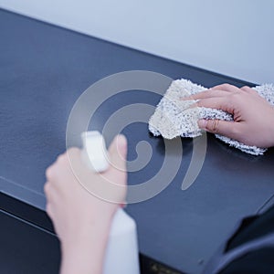 Woman housekeeper using rag and spraying bottle to clean the table surface