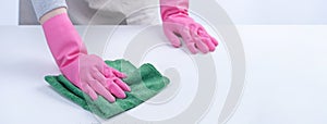 Woman housekeeper wearing protective gloves and using rag to wipe clean the table surface